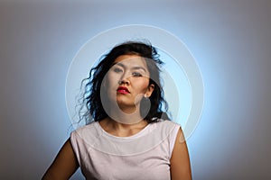Asian model with a cryptic and insightful look on a background with blue highlight. Studio portrait of a colorful and young asian