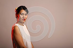 Asian model with a cryptic and insightful look. Studio portrait of a colorful and young asian. Seductive look of a girl with copy