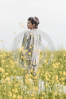 An Asian model poses in a field of yellow flowers for a clothing brand, polyethylene is the main props for a photo shoot