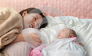 Asian mom and baby sleeping in bed, They smile together, Living lifestyle family indoors concept