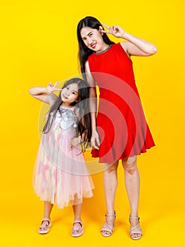 Asian mom and daughter taking portrait photo together on yellow background