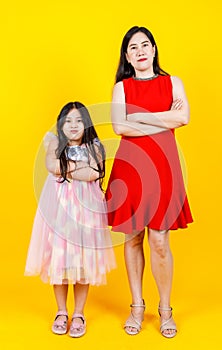 Asian mom and daughter taking portrait photo together on yellow background