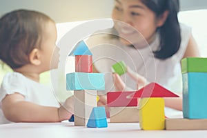 Asian mom and girl kid playing with blocks. Selective focus and