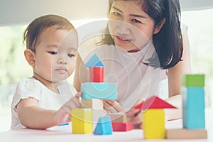 Asian mom and girl kid playing with blocks. Vintage effects and