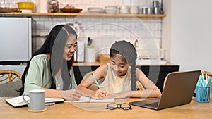 Asian mom helping her daughter doing homework. Concept of Virtual education, homeschooling