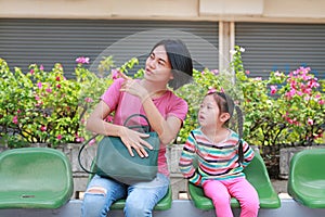 Asian mom and her daughter sitting on public transport bus. Mom pointing something to child girl looking