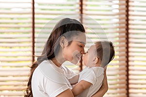 Asian mom holding her baby newborn in hand and kissing on baby nose sweet and lovely.Good moment of Happy mother and infant baby