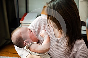 Asian mom holding her crying little baby at home