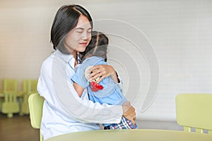 Asian mom hugging daughter on Mother`s day in thailand. Little girl Pay respect and give Thai traditional jasmine garland to mom