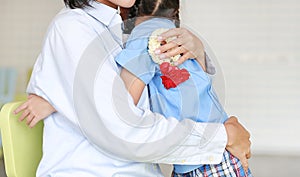 Asian mom hugging daughter on Mother`s day in thailand. Little girl Pay respect and give Thai traditional jasmine garland to mothe