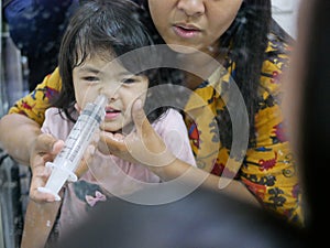 Asian mom rinsing her baby`s stuffy nose using a syringe of saline water