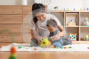 Asian mom teaching baby boy learning and playing toys for development skill at home or nursery room. Happiness mother and baby