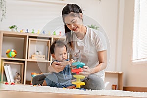 Asian mom teaching baby boy learning and playing toys for development skill at home or nursery room. Happiness mother and baby