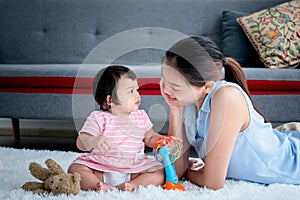 Asian mother and 7 month old daughter sitting on the floor and looking into each other`s eyes