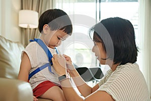 Asian mother adjusting son's backpack