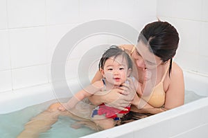 Asian mother and baby girl bathing together in bathtub, Happy lifestyle family concept