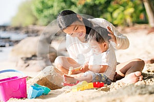 Asian mother and baby play sand and toy togather