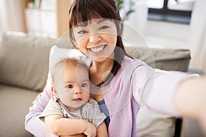 Asian mother with baby son taking selfie at home