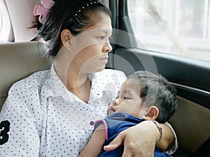 Asian mother carrying her baby while sitting in a moving car without a baby car seat