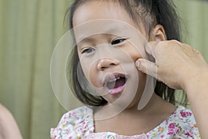 Asian mother and child girl playing pinch cheeks, touch nose funny face