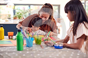 Asian Mother With Children Having Fun With Children Doing Craft On Table At Home