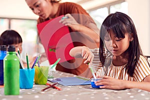 Asian Mother With Children Having Fun With Children Doing Craft On Table At Home