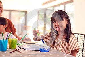 Asian Mother With Children Having Fun With Children Doing Craft On Table At Home