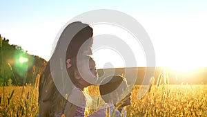 Asian mother with children are sitting in field in summer, point on something, family concept, side view