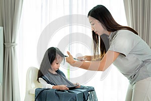 Asian Mother cutting hair to her daughter in living room at home while stay at home safe from Covid-19 Coronavirus during lockdown