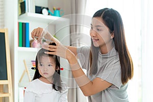 Asian Mother cutting hair to her daughter in living room at home while stay at home safe from Covid-19 Coronavirus during lockdown