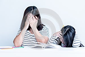 Asian mother and daughter 6 year old are stressed and have a headache from don`t understand homework