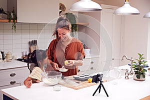 Asian Mother And Daughter Baking Cupcakes In Kitchen At Home Whilst On Vlogging On Mobile Phone photo