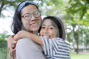 Asian mother and daughter hug each and smiling  other at the park, Happy family concept