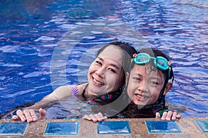 Asian mother and daughter hugging and smilling at the swimming pool