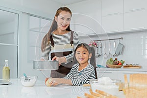 Asian mother and Daughter making bakery in home kitchen counter together with bread on the foreground