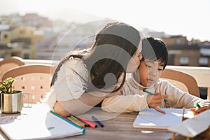 Asian mother doing homeworks with his little son outdoor on patio at home - Focus on child face