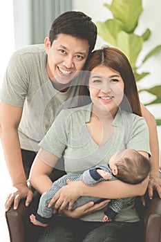 Asian Mother And Father At Home With Baby.