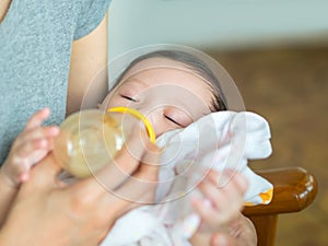 Asian mother feeding bottle her baby while baby sleeping and hol