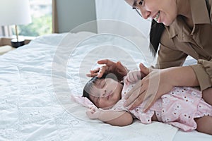 An Asian mother is happily caring for and putting her newborn daughter to sleep.