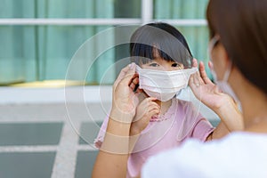 Asian mother help her daughter wearing protection mask to protect the coronavirus Covid-19 outbreak situation before go to school