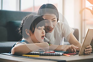 Asian Mother helping her daughter doing homework in online education on internet on Digital Tablet during quarantine period in