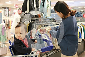 Asian mother and her baby shopping in clothing store