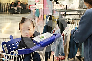 Asian mother and her baby shopping in clothing store