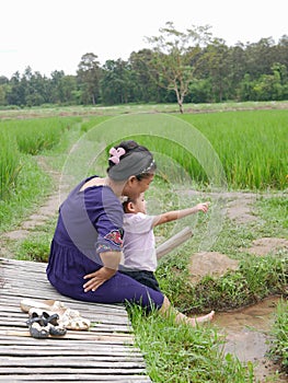 Asian mother and her little baby girl enjoy spending time together in a rice field