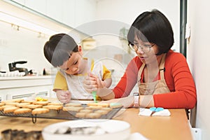 Asian Mother and her Little boy decorating cookies