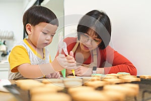 Asian Mother and her Little boy decorating cookies