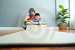 Asian mother and her little son enjoying rolling exercise mat