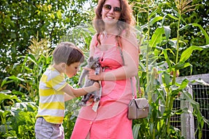 Asian mother and her son playing with cat in the park