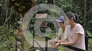 Asian mother and her teenager daughter enjoy to see beautiful scenery of tropical forest during hiking trip in Thailand.