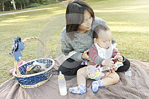 Asian Mother hold baby when family picnic in the park